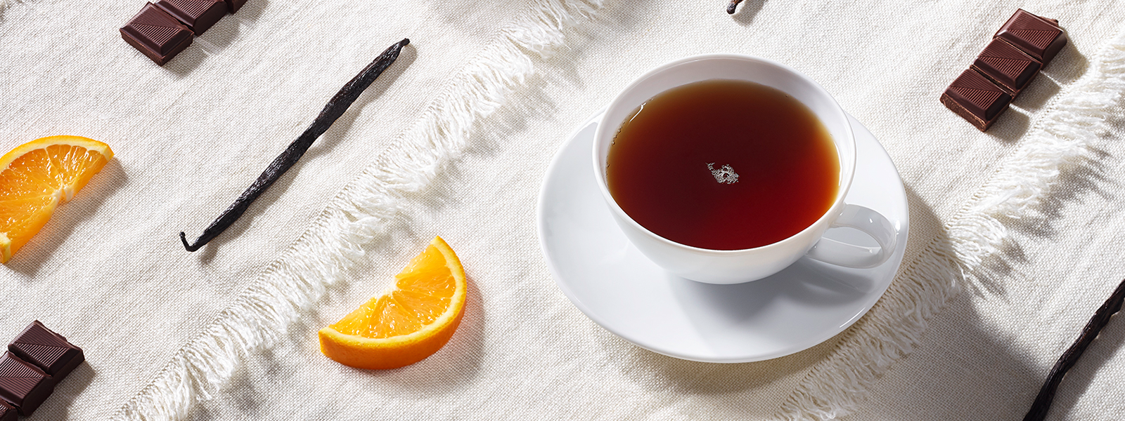 Teetasse mit Stücken von Schokoladen und Orangen und Vanilleschoten