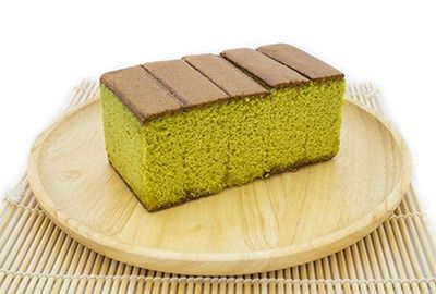 Scheibe Matcha-Kuchen auf einem runden Holzteller mit Bambusmatte