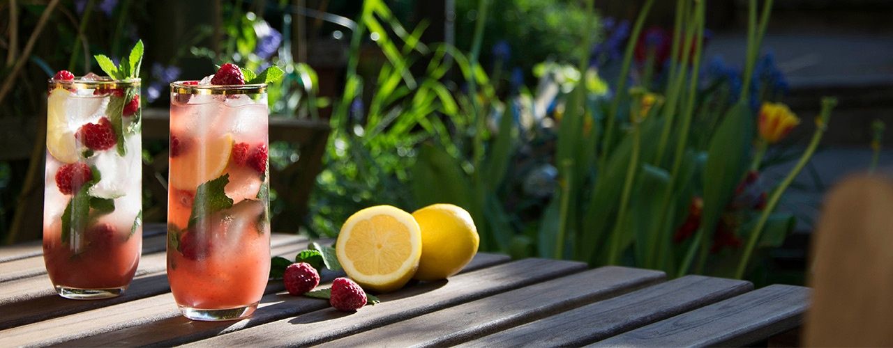 Zwei Gläser mit Eistee und Früchten auf einem sonnigen Tisch