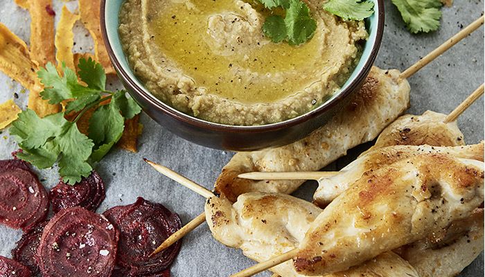 Gegrillte Hähnchenspieße mit cremigem Hummus, serviert mit Rote-Bete-Chips