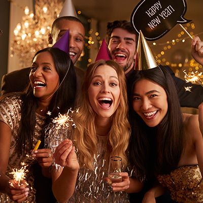 Freundesgruppe feiert fröhlich Silvester mit Partyhüten und Wunderkerzen