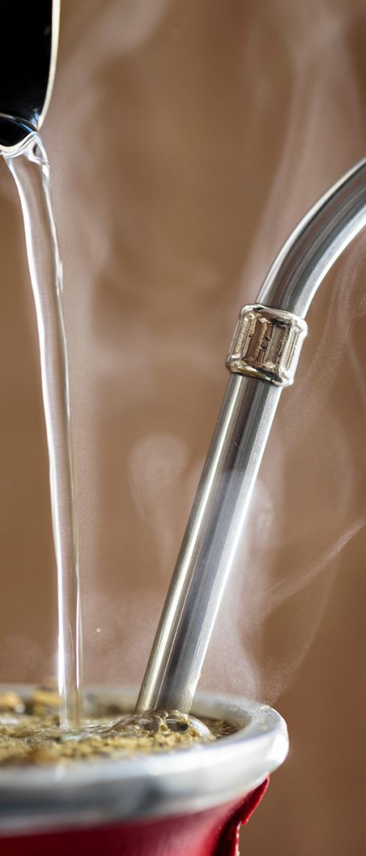 Heißes Wasser wird in ein traditionelles Mate-Gefäß mit Bombilla gegossen