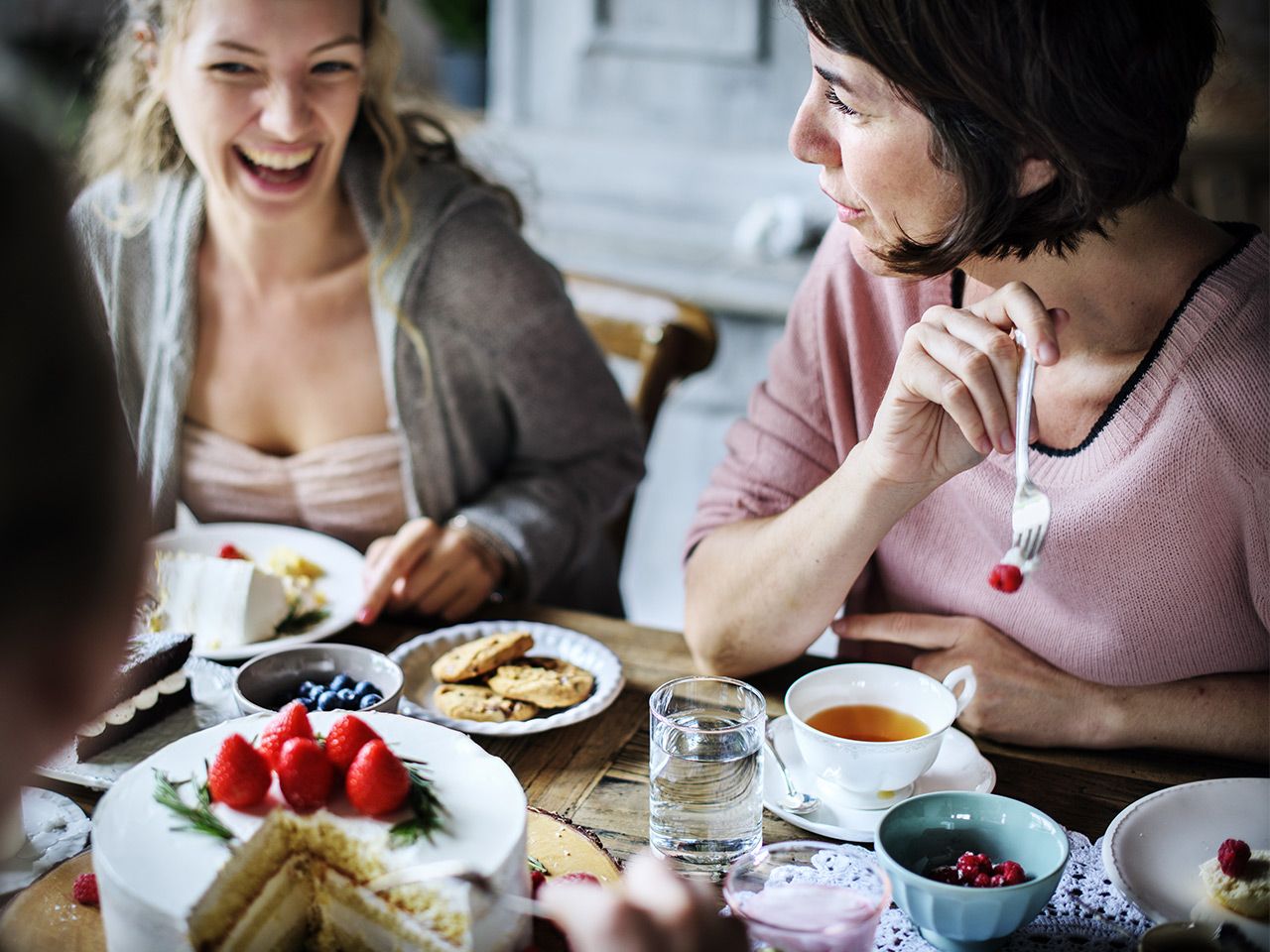 Zwei Frauen lachen und genießen Tee und Kuchen 