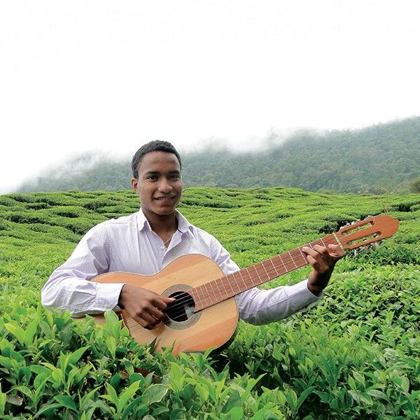 Mann mit Gitarre in Teegarten mit nebelverhangenen Bergen im Hintergrund
