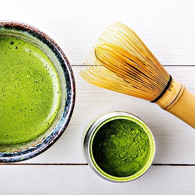 Matcha-Tee mit Bambusbesen, Teeschale und Dose mit grünem Teepulver