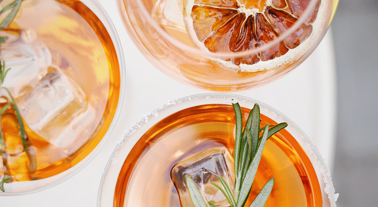 Eistees mit Eiswürfeln, Rosmarinzweigen und getrockneter Orangenscheibe in Gläsern