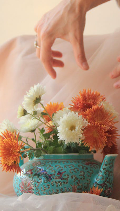 Türkise Teekanne mit orientalischem Muster als Vase für orange-weiße Blumen